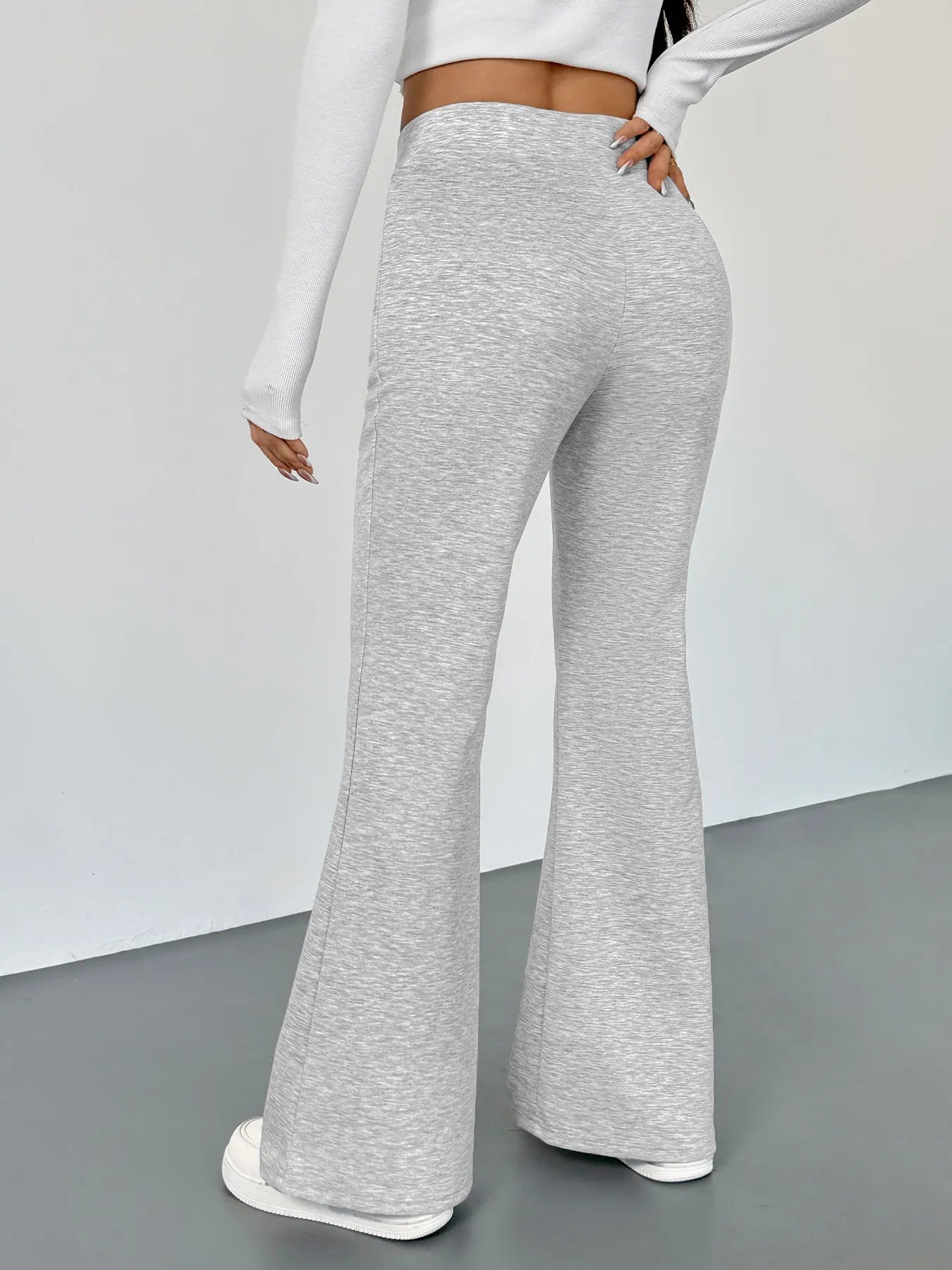 Person wearing gray flared pants on a plain background
