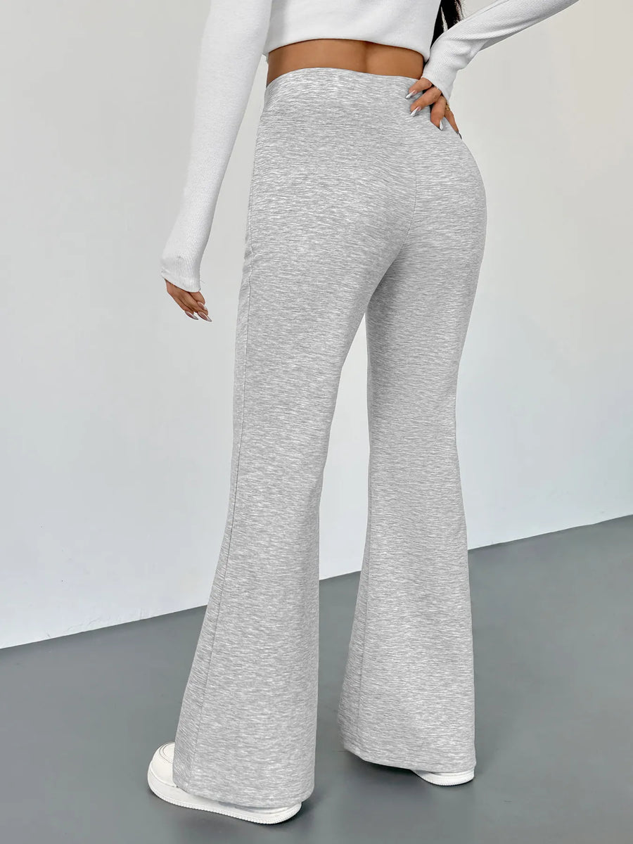 Person wearing gray flared pants on a plain background