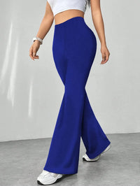 Person wearing blue flared pants and white top on a plain background