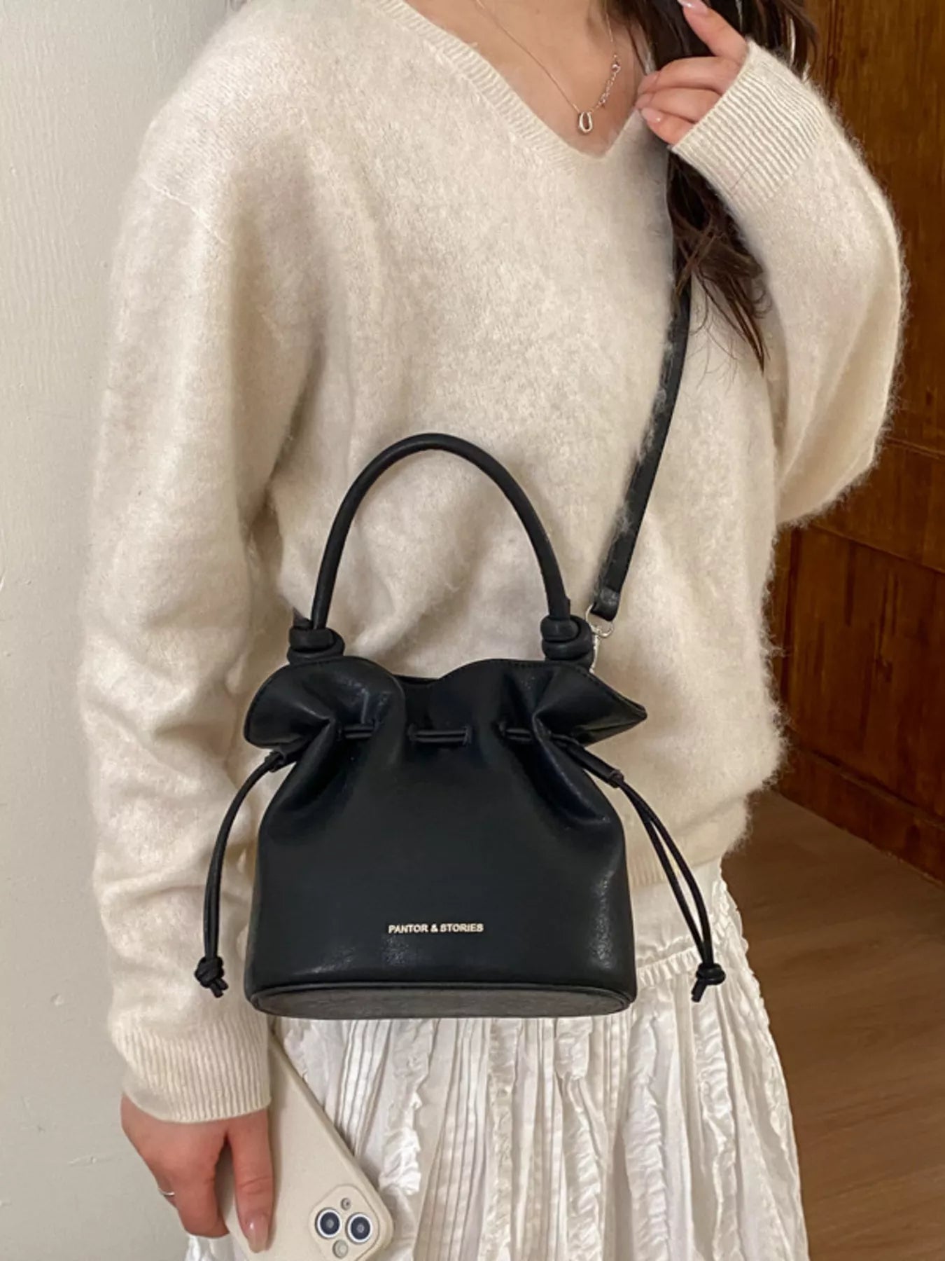 Person holding a black handbag with 'FENDI' branding against a neutral background
