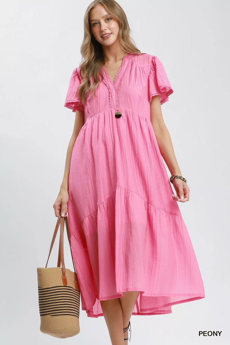 Woman wearing a pink dress holding a straw bag on a white background