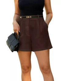 Person wearing brown shorts and a black top, holding a black handbag on a white background