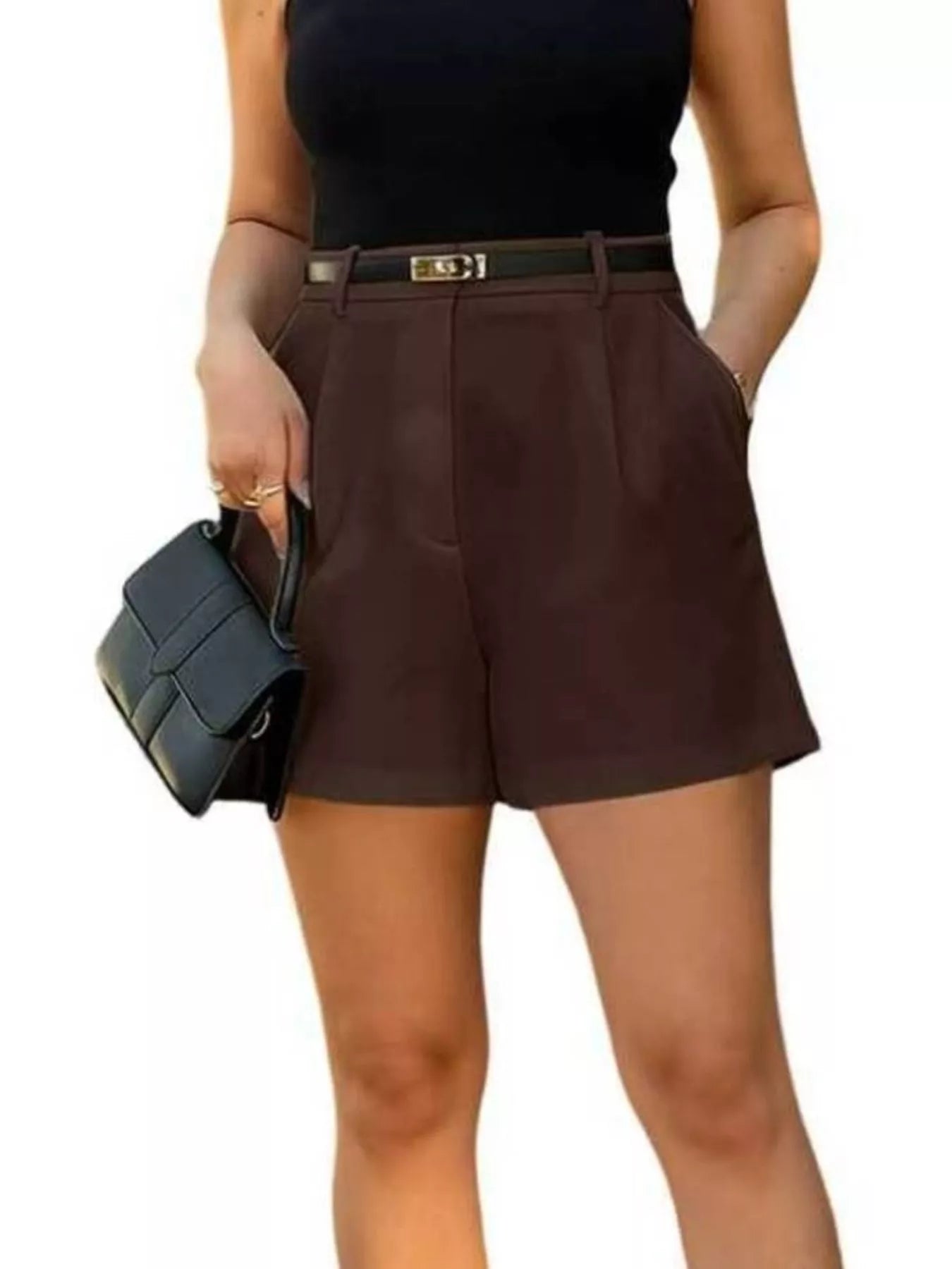 Person wearing brown shorts and a black top, holding a black handbag on a white background