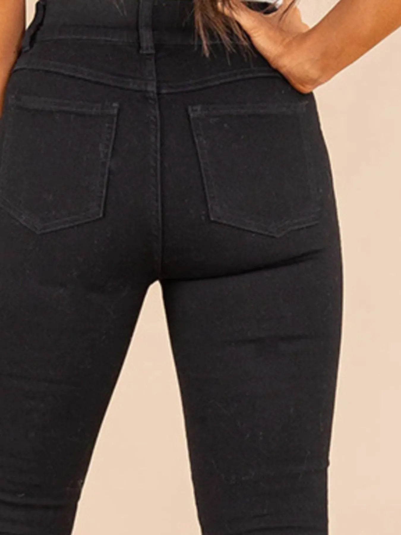 Black jeans worn by a person on a beige background
