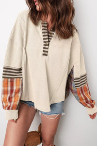 Person wearing a beige cardigan with plaid sleeves on a white background
