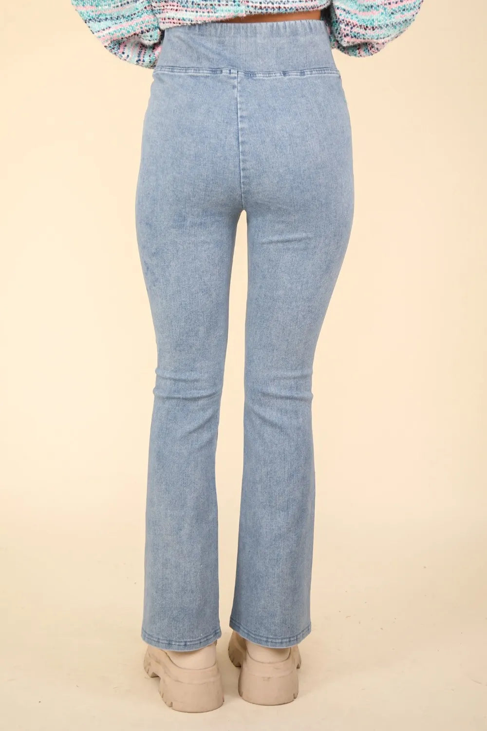 Light blue jeans worn by a person on a beige background