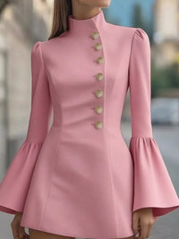 Pink dress with bell sleeves and gold buttons on a blurred background
