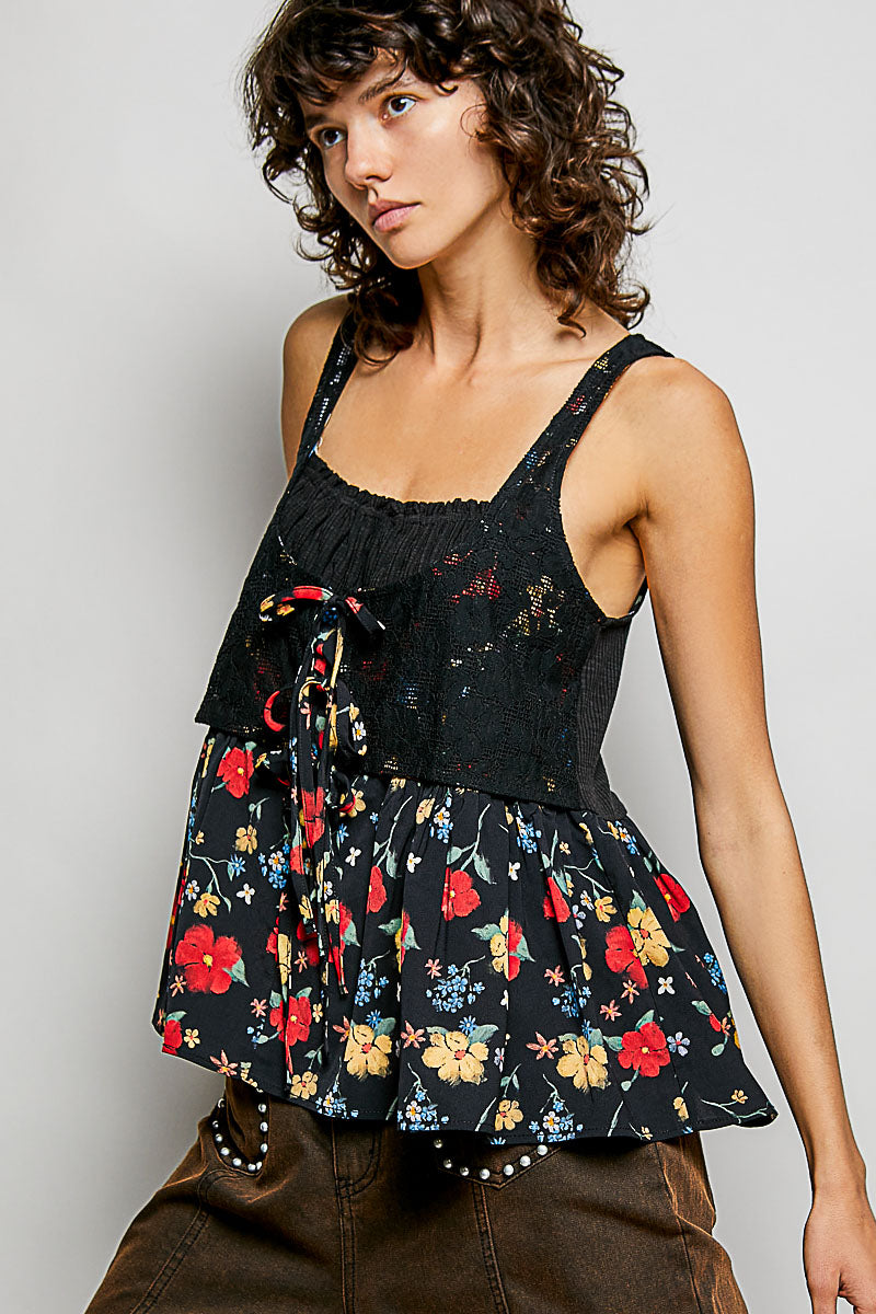 Woman wearing a black floral peplum top against a plain background