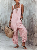 Woman wearing a pink striped jumpsuit holding a woven bag against a textured wall.