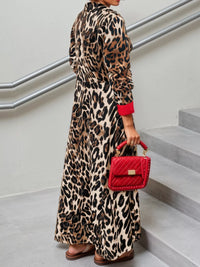Person wearing a leopard print dress holding a red handbag on a staircase.