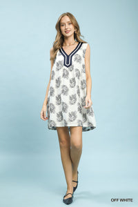 Woman wearing a floral dress with a blue neckline against a light blue background