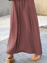Brown wide-leg pants worn by a person on a stone pavement.