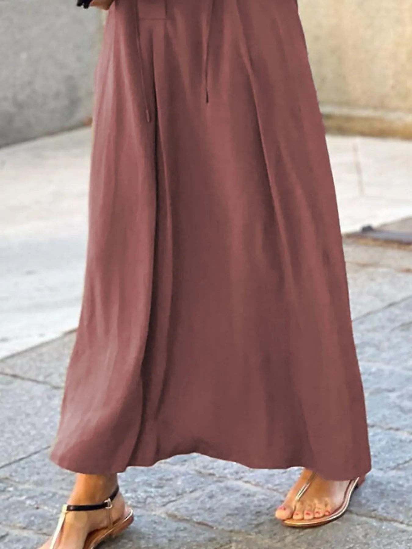 Brown wide-leg pants worn by a person on a stone pavement.