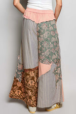 Person wearing a patchwork skirt with floral and striped patterns on a plain background