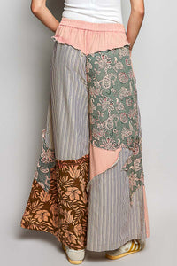 Person wearing a patchwork skirt with floral and striped patterns on a plain background