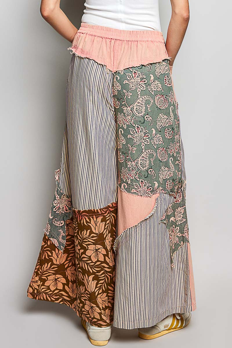 Person wearing a patchwork skirt with floral and striped patterns on a plain background