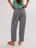 Person wearing a green checkered shirt and black and white checkered pants on a plain background