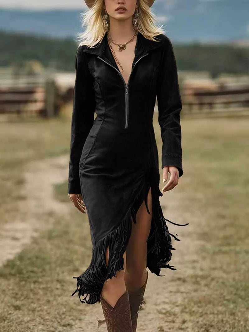 Woman in a black dress with fringe walking on a dirt path in a rural setting.