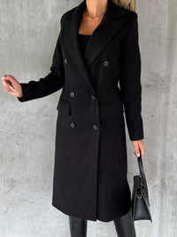Person wearing a black coat against a gray background
