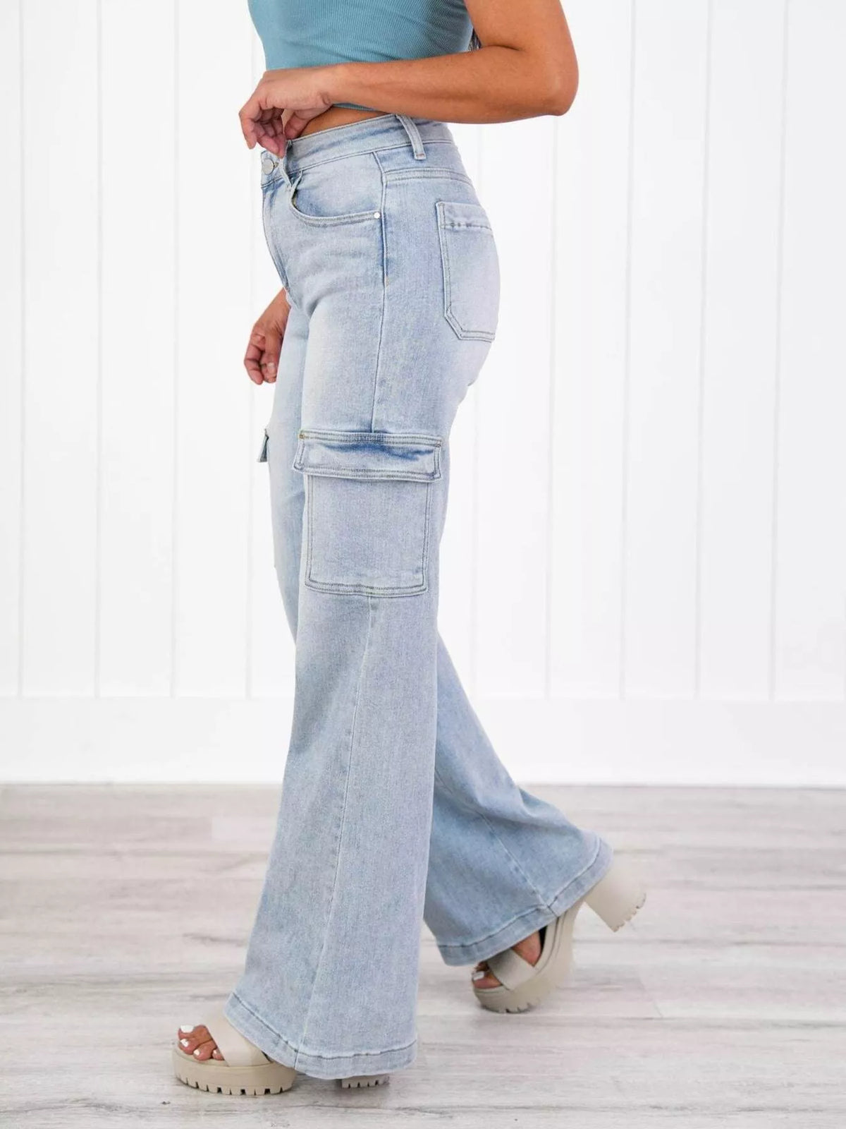 Light blue flared jeans worn by a person on a white wooden floor.