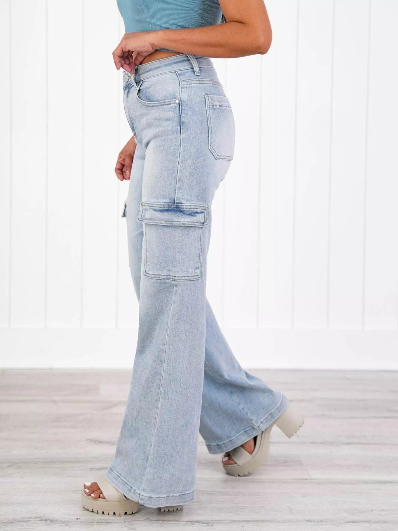 Light blue flared jeans worn by a person on a white wooden floor.
