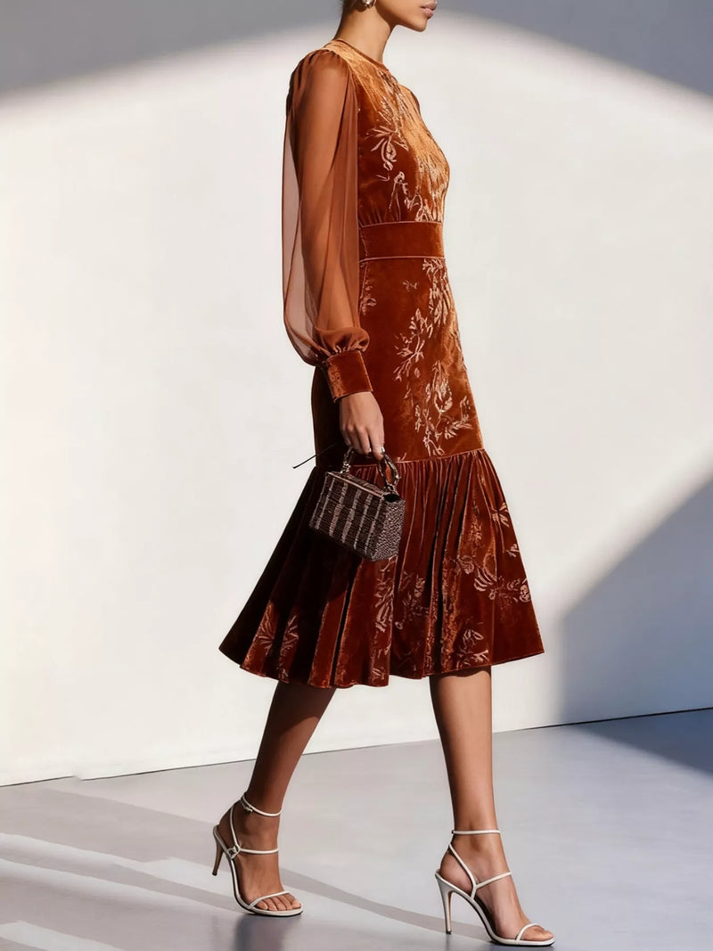 Woman wearing a brown floral dress with sheer sleeves against a white background
