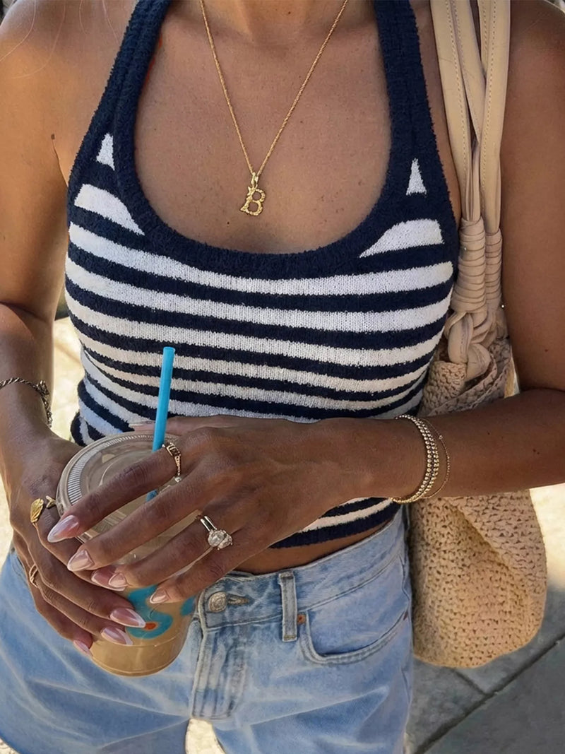 Person wearing a striped tank top and holding a drink with a straw.