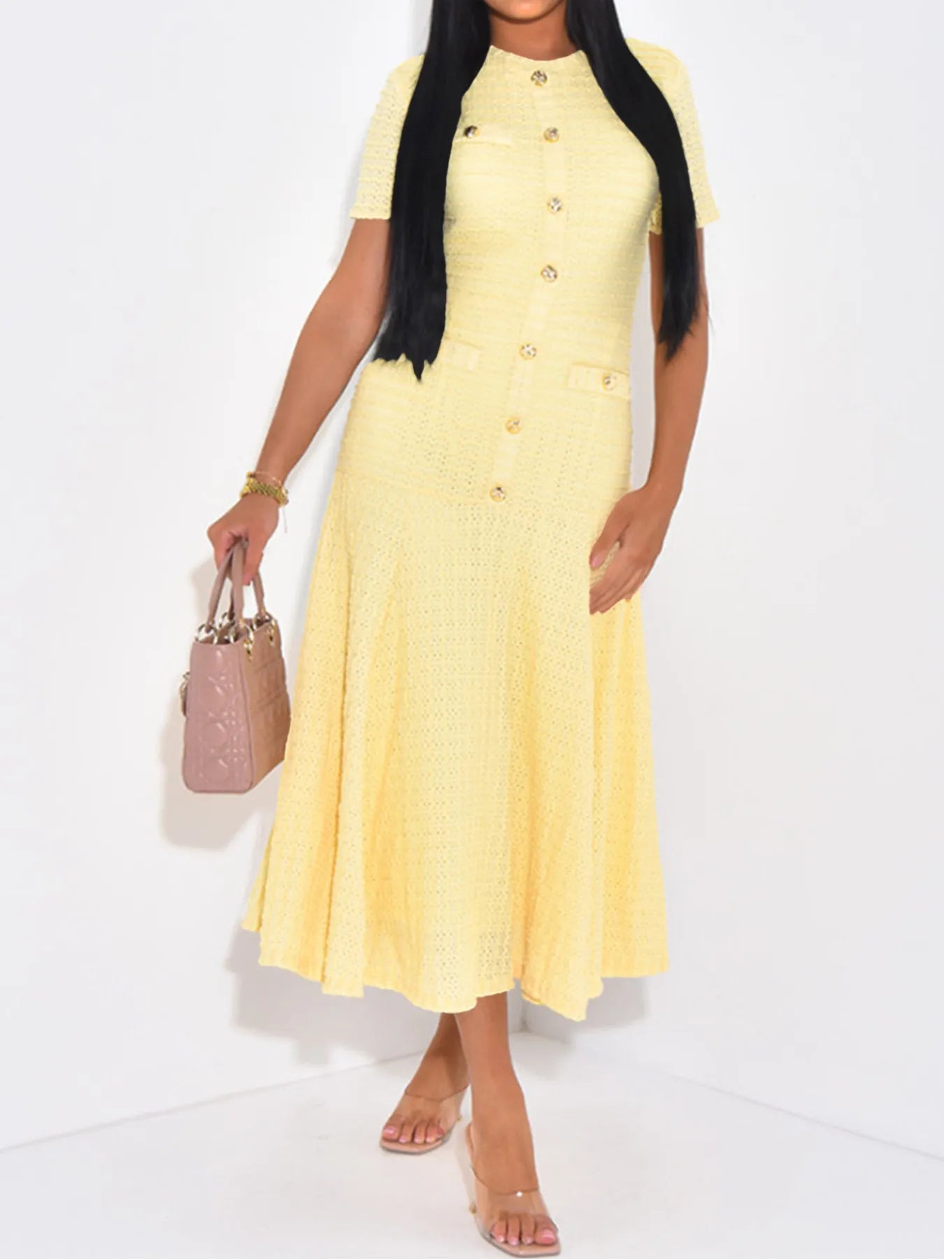 Woman wearing a yellow dress holding a pink handbag on a white background