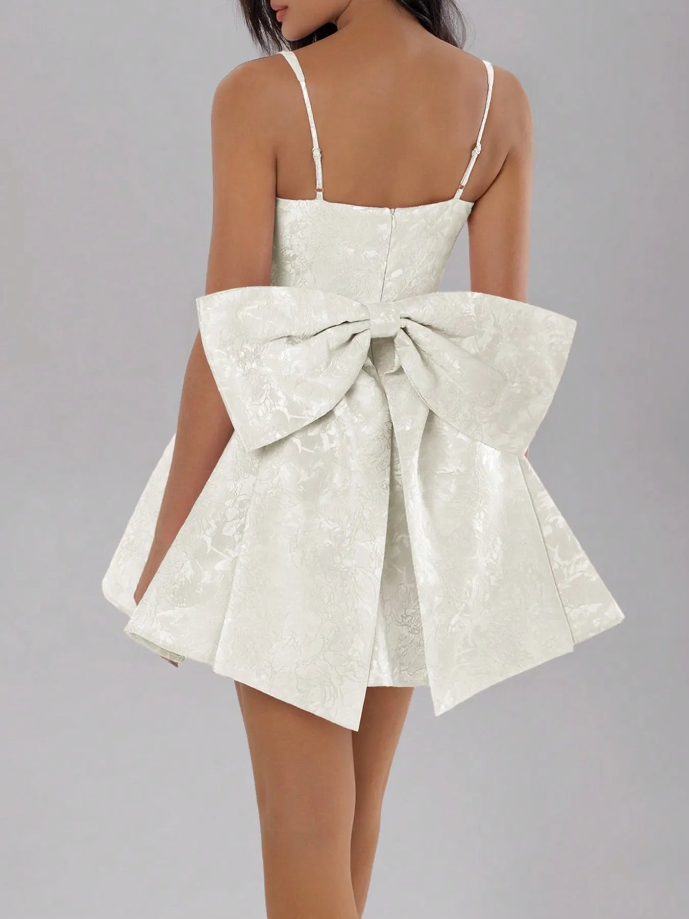 White dress with a large bow detail on a gray background