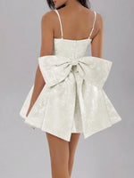 White dress with a large bow detail on a gray background