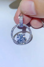 Close-up of a diamond earring held between fingers on a light background