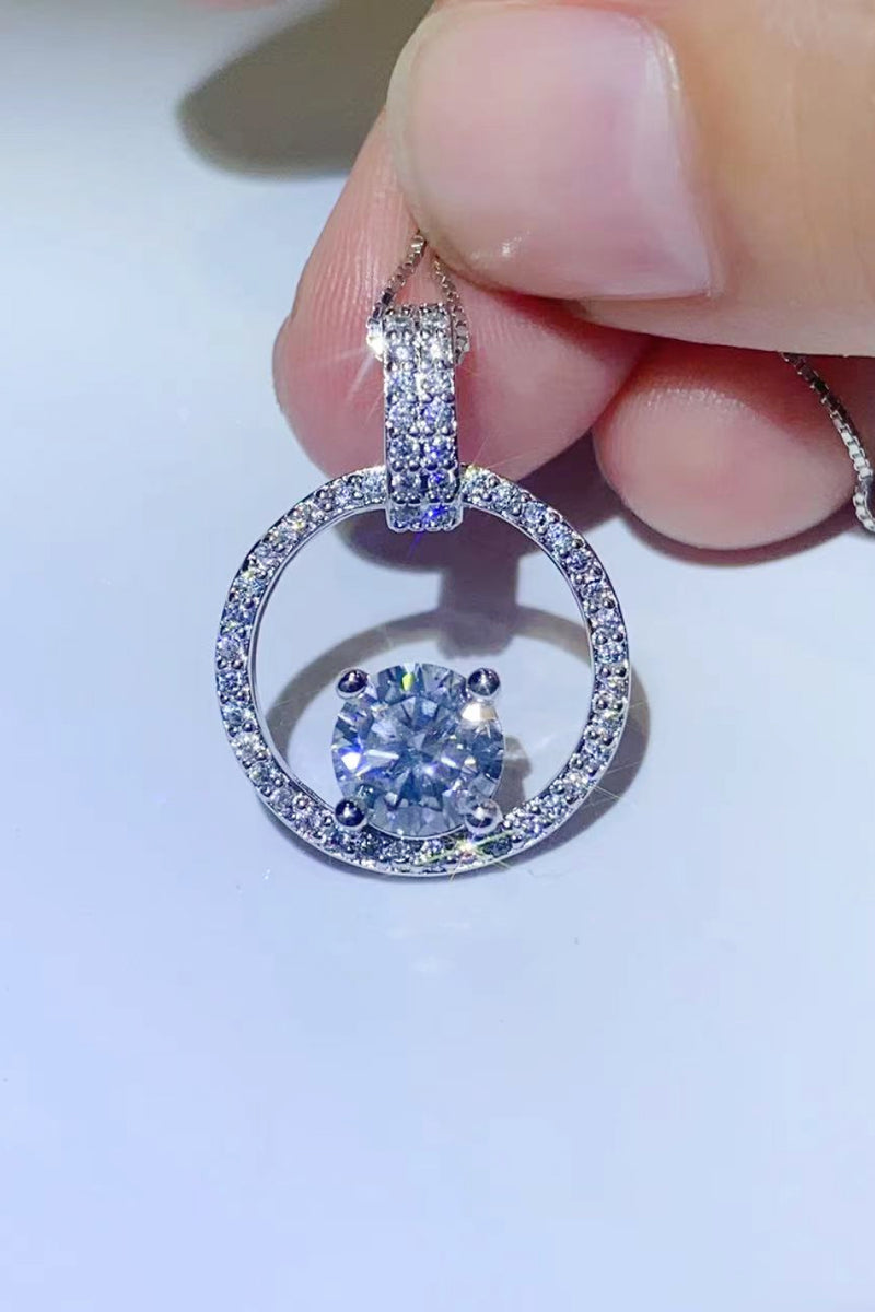 Close-up of a diamond earring held between fingers on a light background