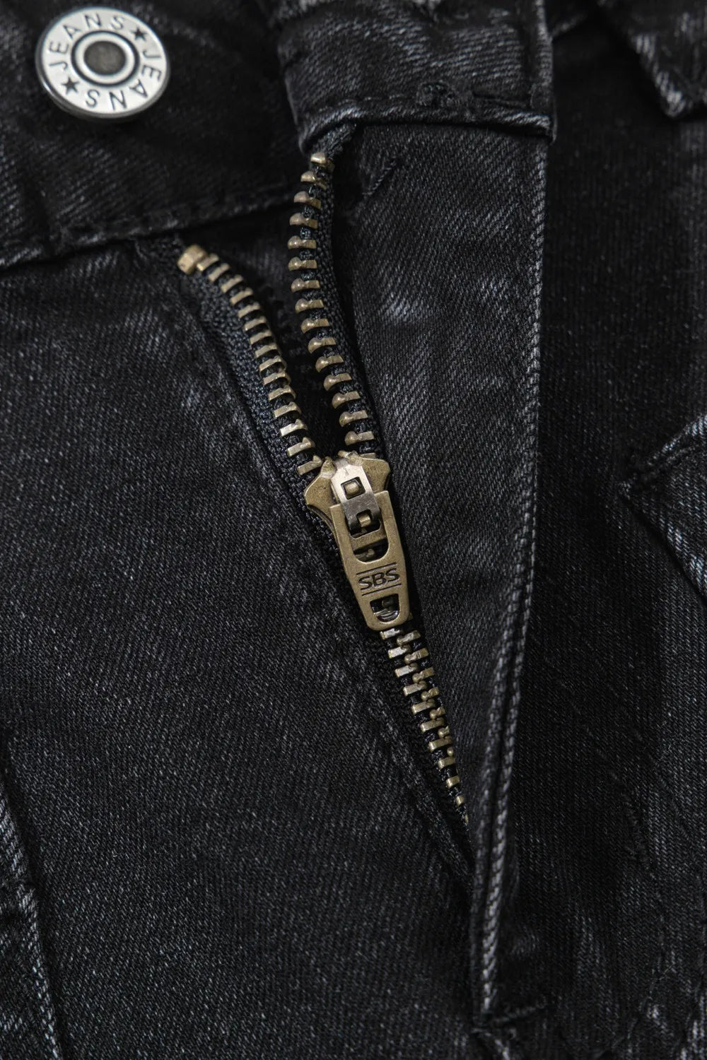 Close-up of a black denim jacket with a brass zipper