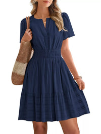 Woman wearing a navy blue dress holding a brown bag on a white background
