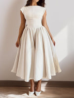 Woman wearing a white dress against a plain background