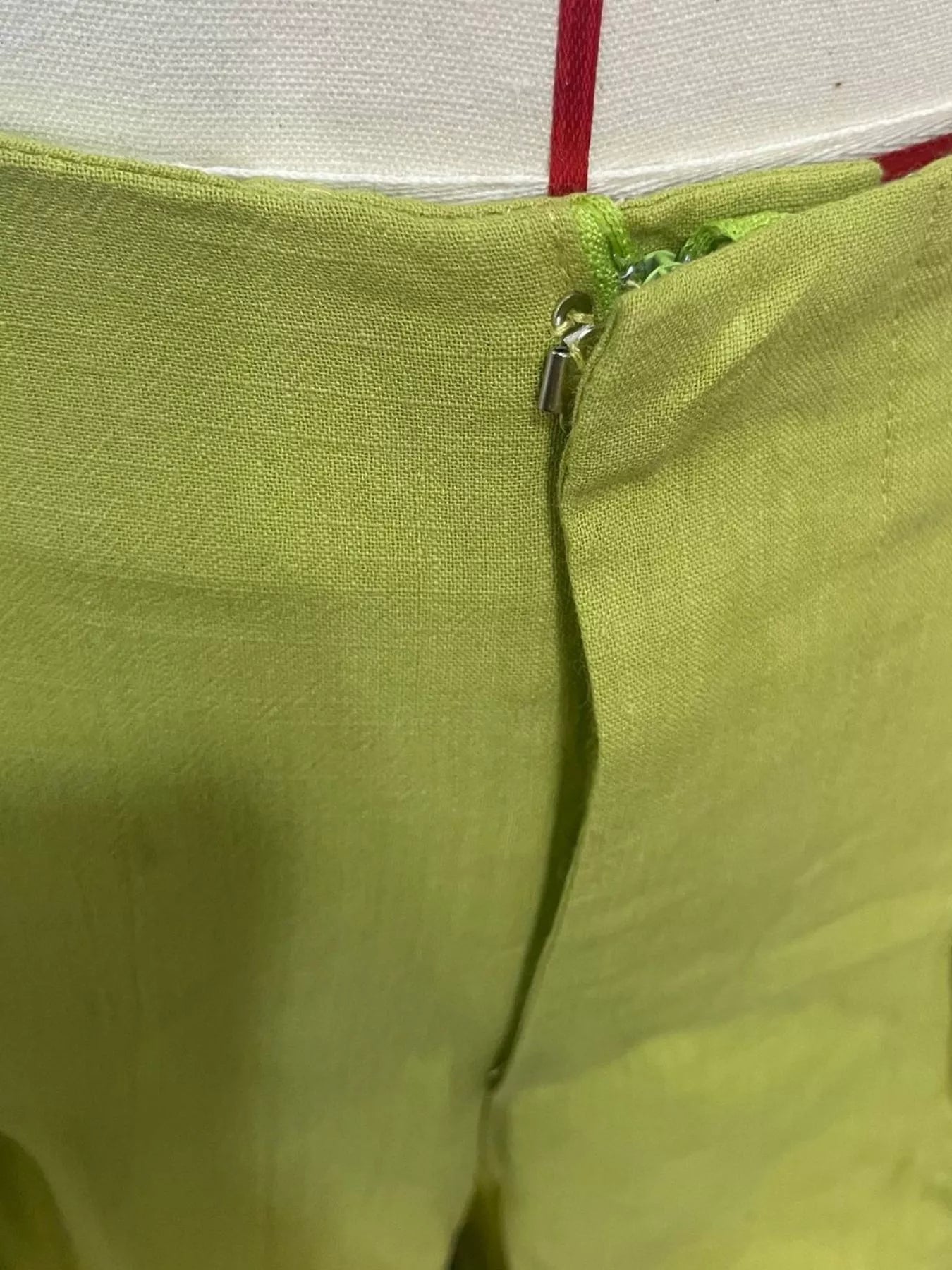Close-up of a green fabric with a zipper, on a white background.