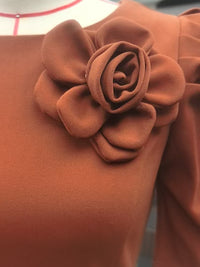 Brown fabric with a flower-shaped brooch on a matching brown background