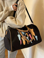 Person holding a black duffel bag with colorful cat illustrations against a neutral background