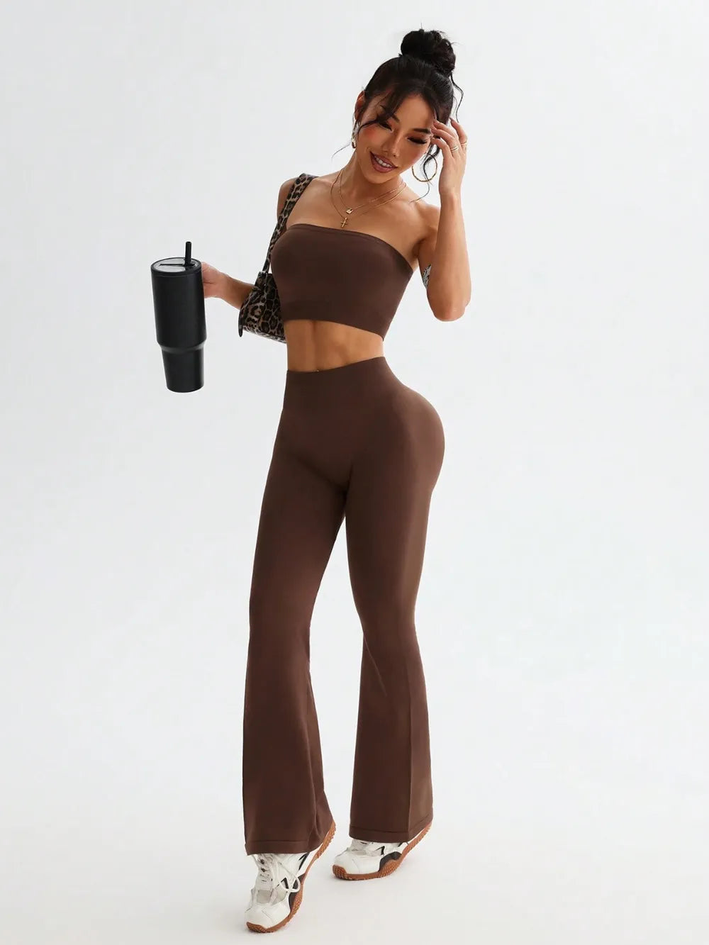 Woman wearing a brown outfit holding a black tumbler on a white background