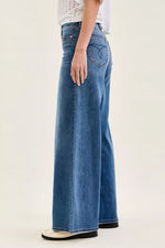 Person wearing blue wide-leg jeans on a plain background