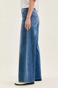 Person wearing blue wide-leg jeans on a plain background