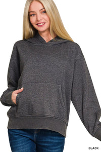 Woman wearing a gray hoodie with a plain background