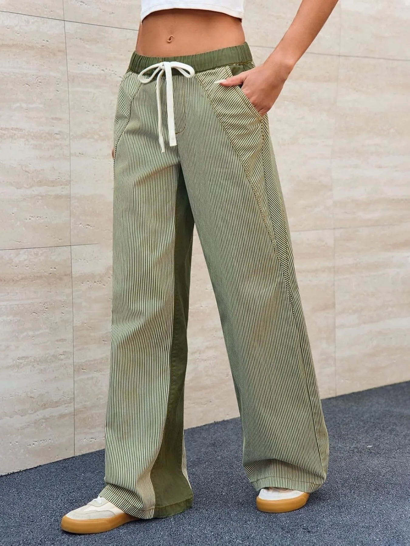 Person wearing green corduroy pants with a beige wall background