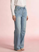 Person wearing light blue jeans on a pink background