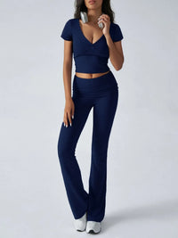 Woman wearing a navy blue outfit with a top and flared pants on a white background