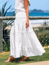 Person wearing a white dress with a blurred background of a fence and grass.