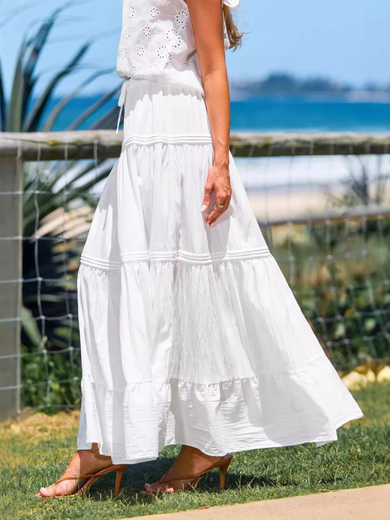Person wearing a white dress with a blurred background of a fence and grass.