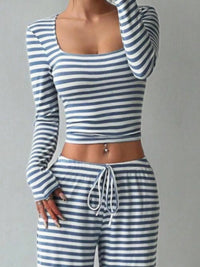 Person wearing a blue and white striped long-sleeve top and pants on a gray background