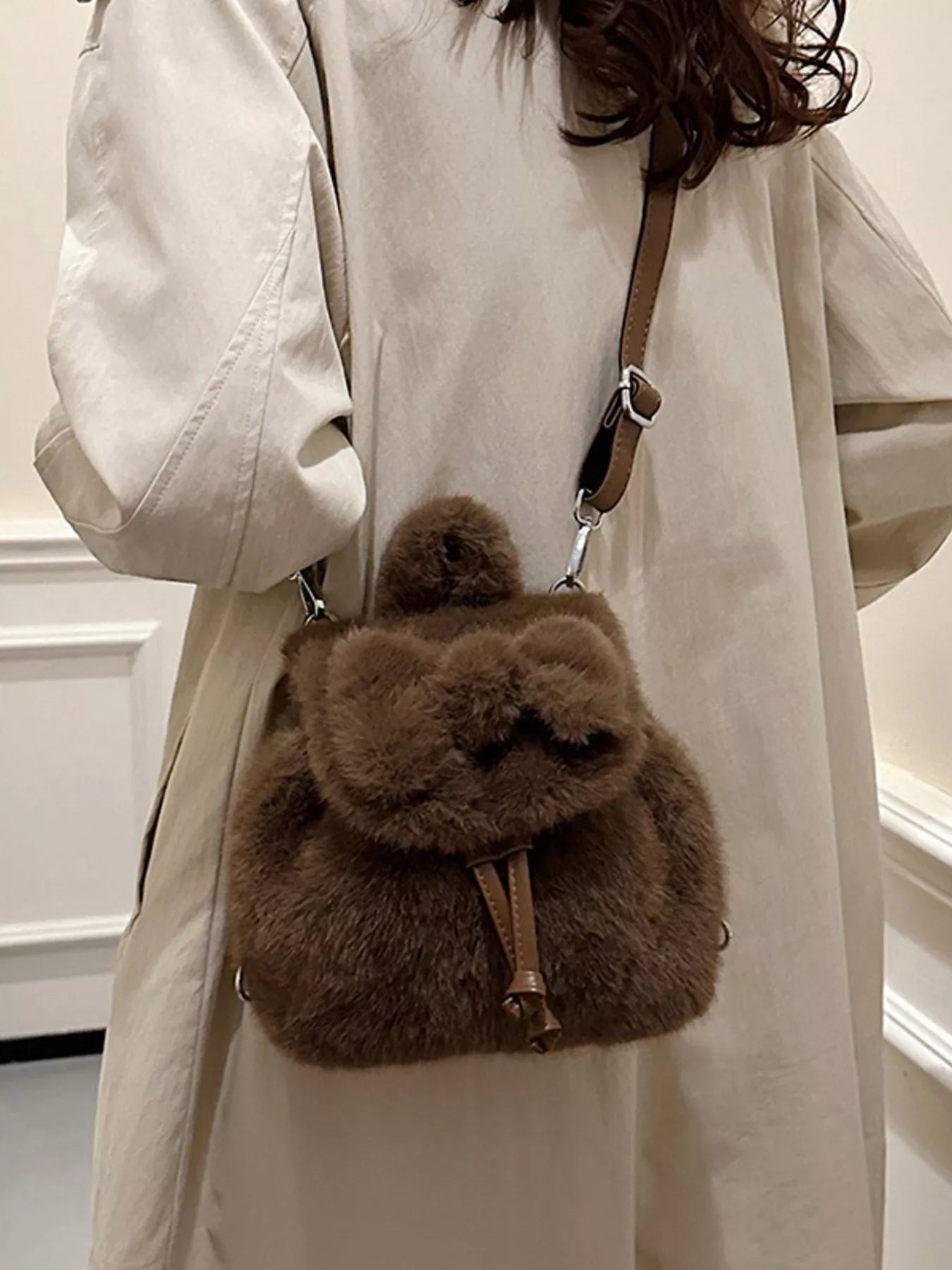 Person wearing a beige coat with a brown fluffy backpack.