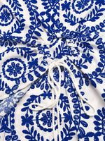 White fabric with blue floral patterns and a white drawstring.
